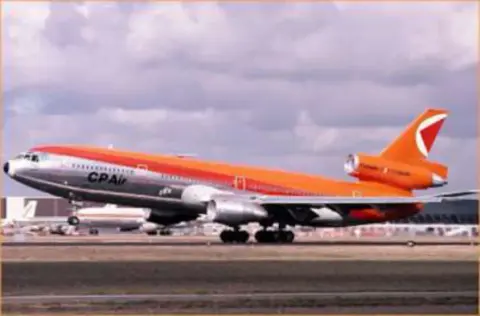 An orange and white airliner on the ramp