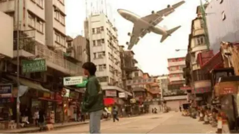 An airliner passing low over a crowded city street