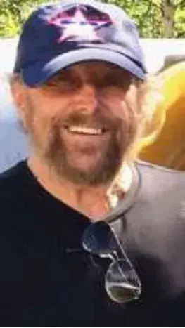 A smiling man in a cap and sunglasses