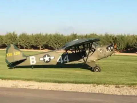 A green military-style Cub on a grass strip
