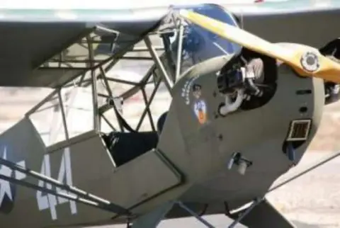 Close-up of the cockpit of an olive drab Piper Cub