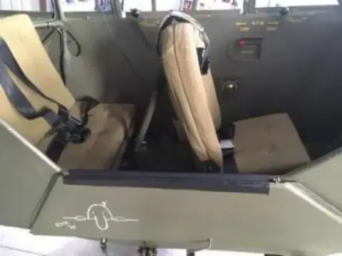 The front and rear seats inside an olive drab Piper Cub