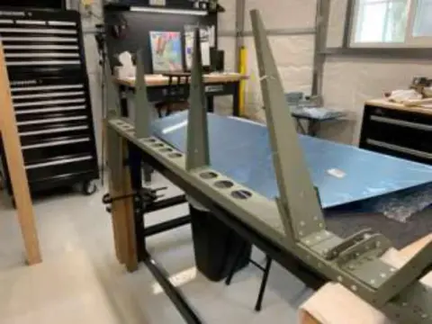 An aircraft wing skin on a stand in a workshop