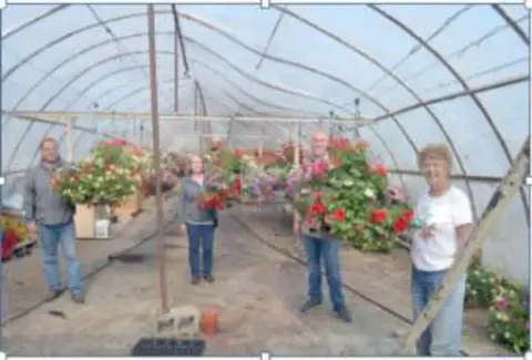 People inside a greenhouse full of hanging flower baskets