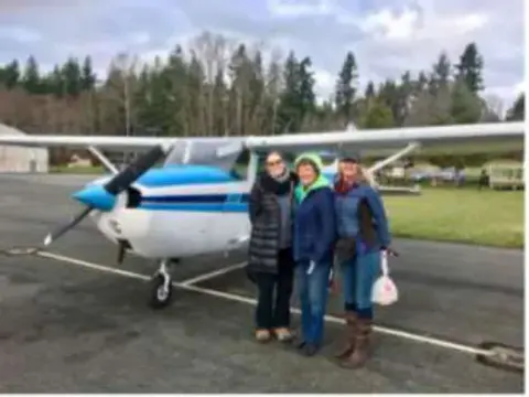 A family standing beside a blue and white airplane