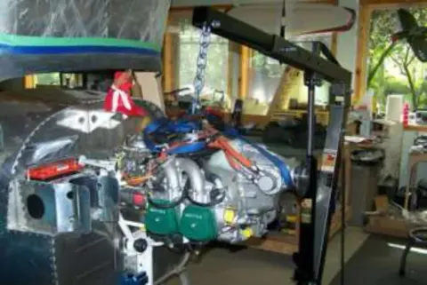 An airplane engine mounted on a fuselage in a garage
