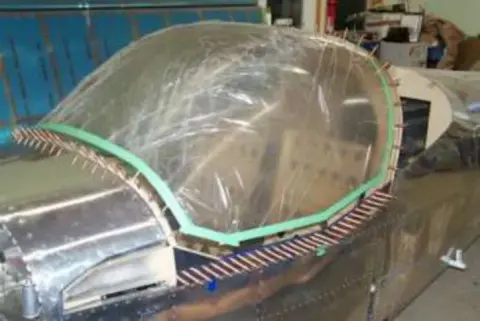 A clear canopy taped onto a metal fuselage