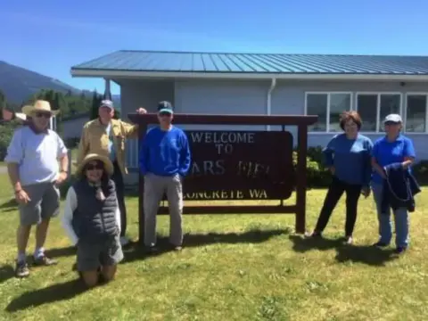 A group of chapter members standing by the airport welcome sign in Concrete, WA