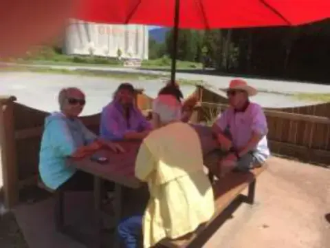 Another table of members under a red umbrella
