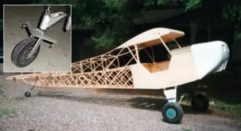 An uncovered fuselage frame with a wing attached on a trailer