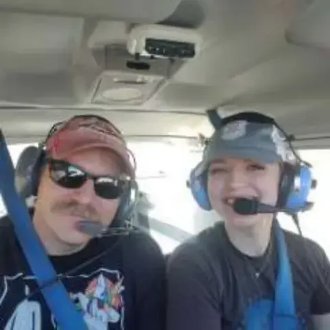 An instructor and student wearing headsets in the cockpit