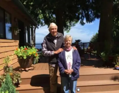 A man and a woman standing on a deck by flower boxes