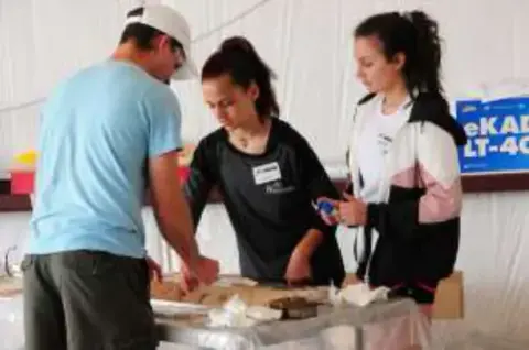 Students and an instructor working on a model at a workbench