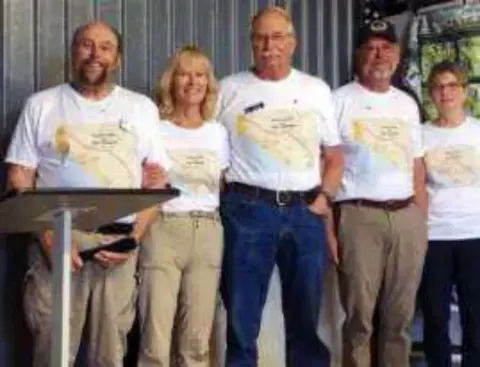 A group in matching white shirts at a hangar