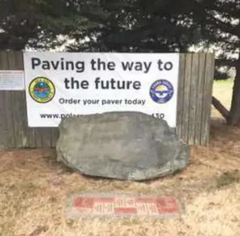 The Paving the way to the future sign above the boulder and the patio pavers