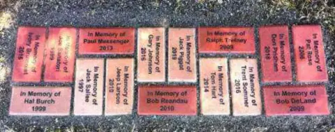Engraved memorial pavers, each reading In Memory of with a name and a year