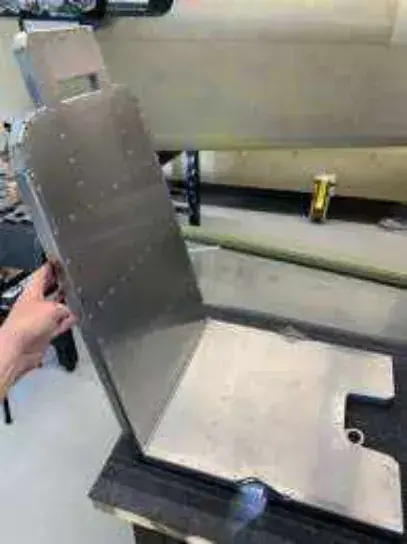 A metal seat back being fitted in a workshop