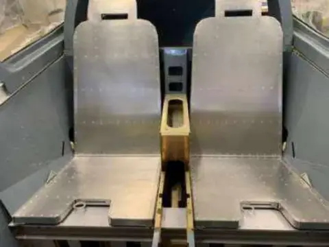 Two metal seats fitted in an airplane cockpit under construction