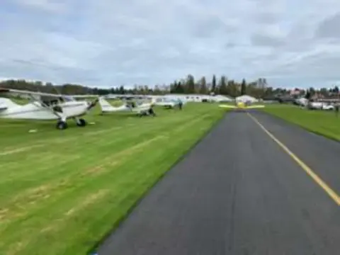 Airplanes parked along a paved runway lined with grass