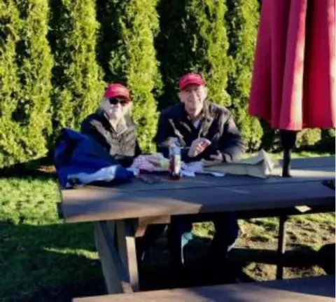 Two men sitting at a picnic table outdoors