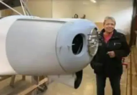 A woman standing next to an engine cowling in a hangar