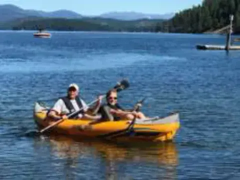 Two people paddling a yellow kayak on a lake