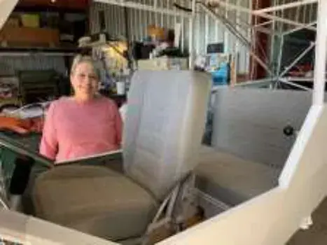 A woman seated among airplane seats being restored in a shop
