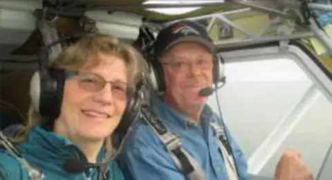 A woman and a man wearing headsets in the cockpit