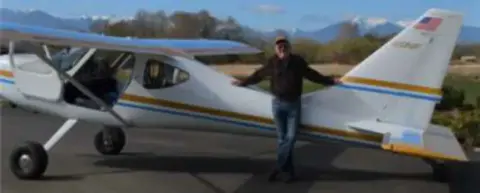 A man standing by the wing of a white high-wing airplane