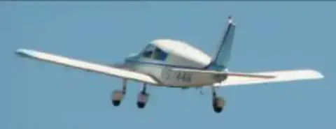 A white low-wing airplane in flight
