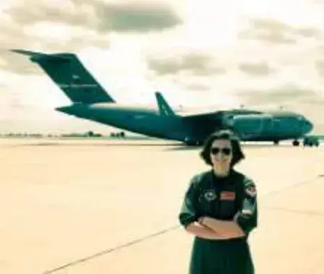 A young woman standing in front of a large military jet transport