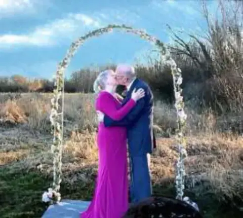 A couple embracing under a wedding arch outdoors