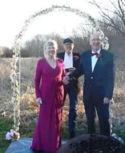 A wedding couple standing under a flowered arch