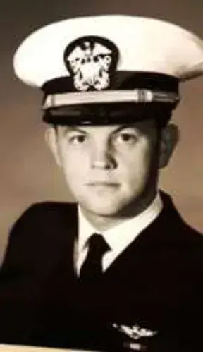 A black and white portrait of a young Navy officer in a white cap