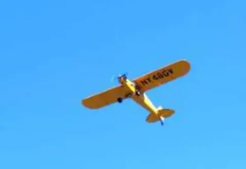 A yellow Cub flying against a blue sky