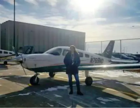 Madeline Patterson standing in front of a white low-wing airplane on the ramp