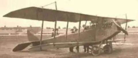 An old photo of a Curtiss Jenny biplane on the ground