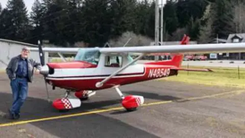 A man next to a red and white Cessna on the ramp