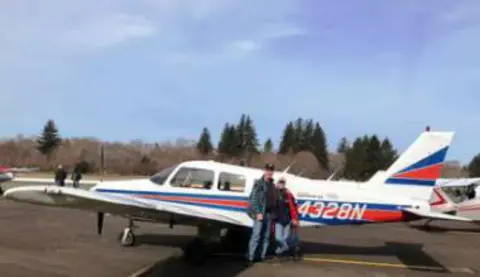 A red, white and blue low-wing airplane parked on the ramp