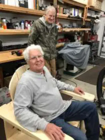 An older man seated in a workshop chair