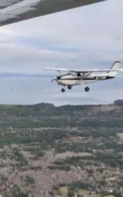 A small airplane in flight over a hillside town