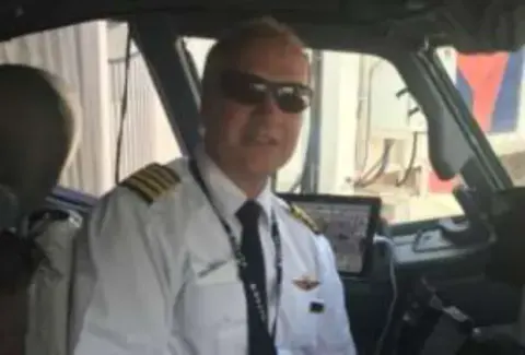 A smiling airline captain in the cockpit