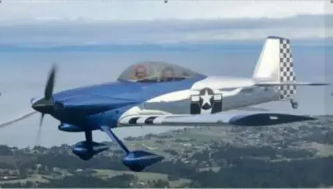 A blue and white low-wing homebuilt airplane in flight