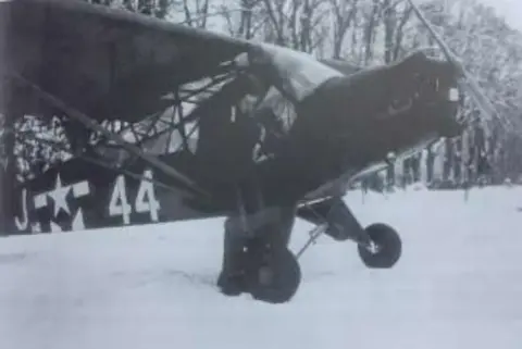 A black and white photo of a military liaison airplane on snow