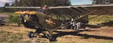 An olive drab liaison airplane parked on grass