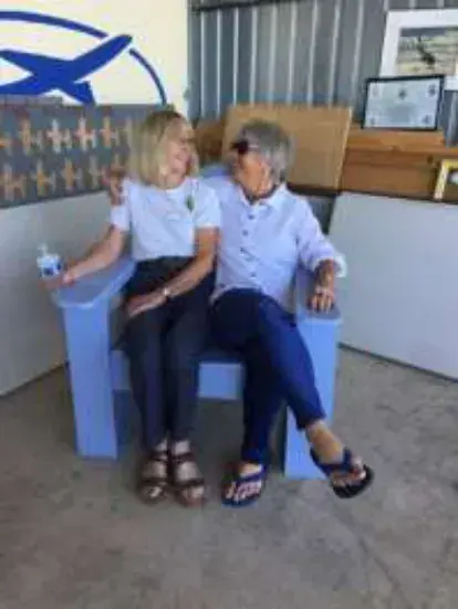 Two women sitting in a blue Adirondack chair