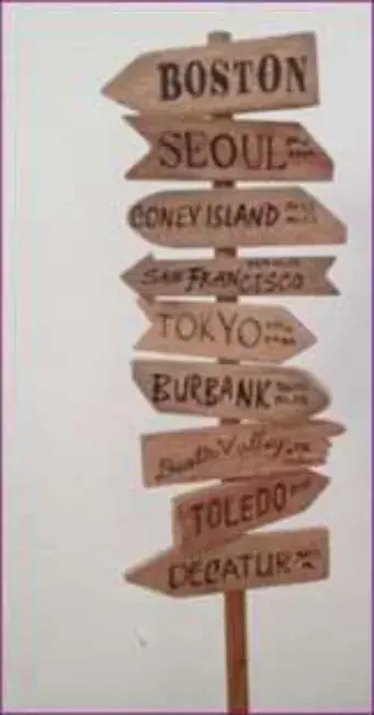 A signpost with arrows naming distant cities, including Boston and Seoul