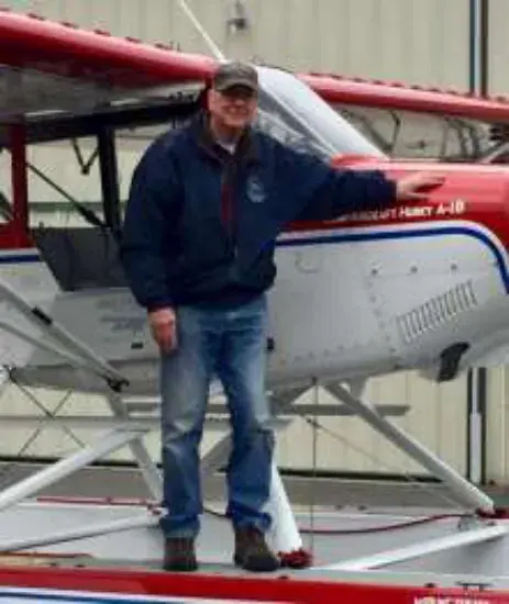 Dave Woodcock standing on the float of his red and white Husky