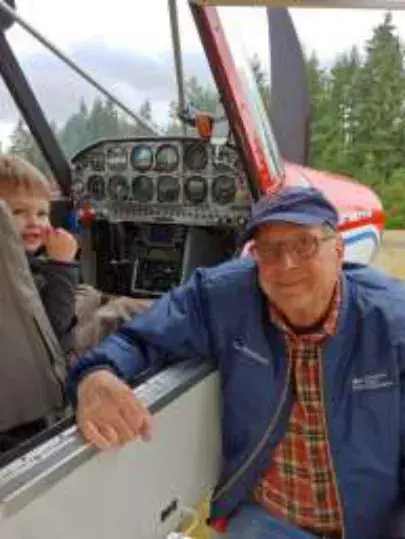 Dave Woodcock and his grandson Grayson beside an airplane cockpit