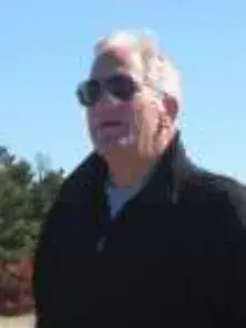A white-haired man in sunglasses and a dark jacket, outdoors